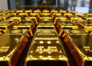 Ilustrasi close-up emas batangan yang tertata rapi di etalase toko, memantulkan kilau cahaya lampu, melambangkan nilai dan kestabilan aset investasi di tengah gejolak ekonomi.